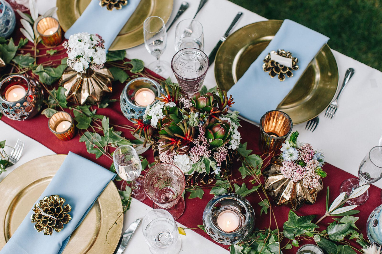 A table set with plates, candles and flowers.