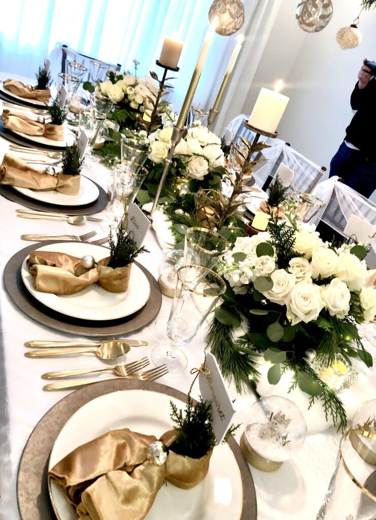 A long table with plates and silverware, candles, and flowers.