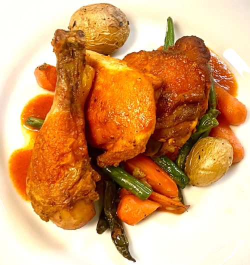 A plate with roasted chicken, green beans, carrots, and potatoes.