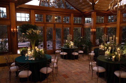 Elegant indoor event setup with round tables and floral centerpieces in a cozy wooden room.