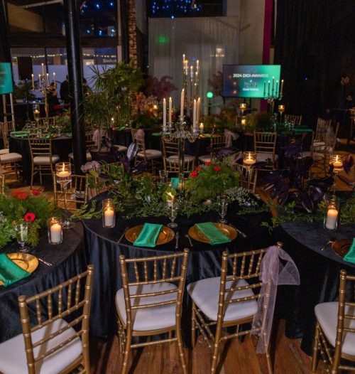 Elegant outdoor dinner setup with candles and lush greenery at night.