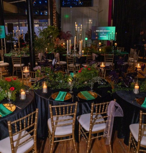 Elegant outdoor dinner setup with candles and lush greenery at night.