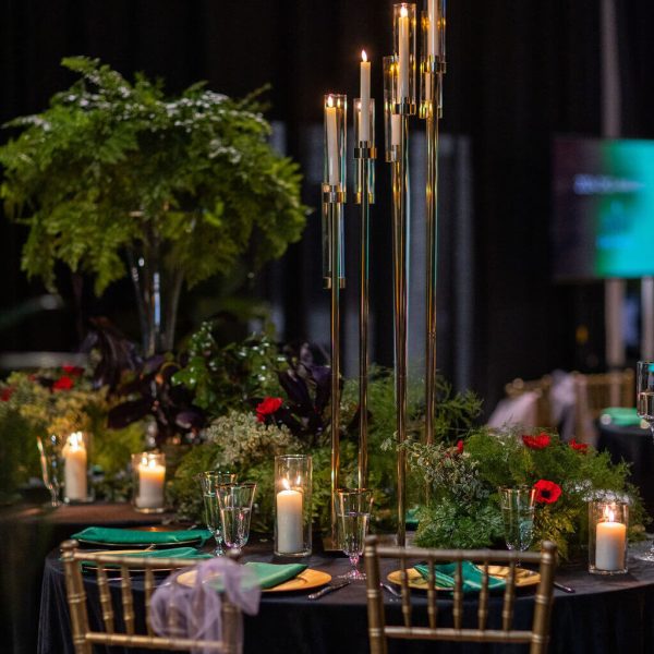 Elegant candlelit table setting with lush greenery and floral centerpiece.