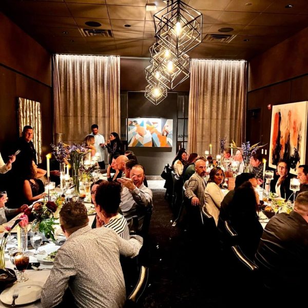 Elegant dinner party with guests enjoying conversation under modern lighting.