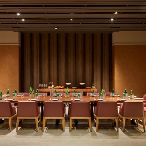 Elegant dining table set with chairs and decor in a warm-toned room.