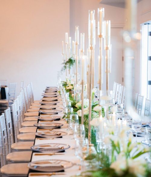 Elegant long dining table set with candles and floral centerpieces for a formal event.